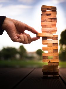 hand of businessman pulling out or placing wood block on the tower. plan and strategy in business. blur for background